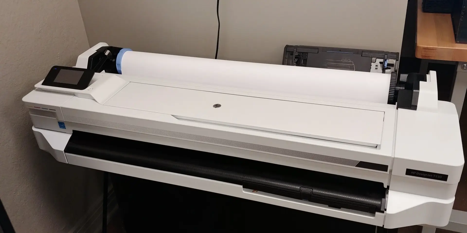 A large, white poster printer sitting in a corner.