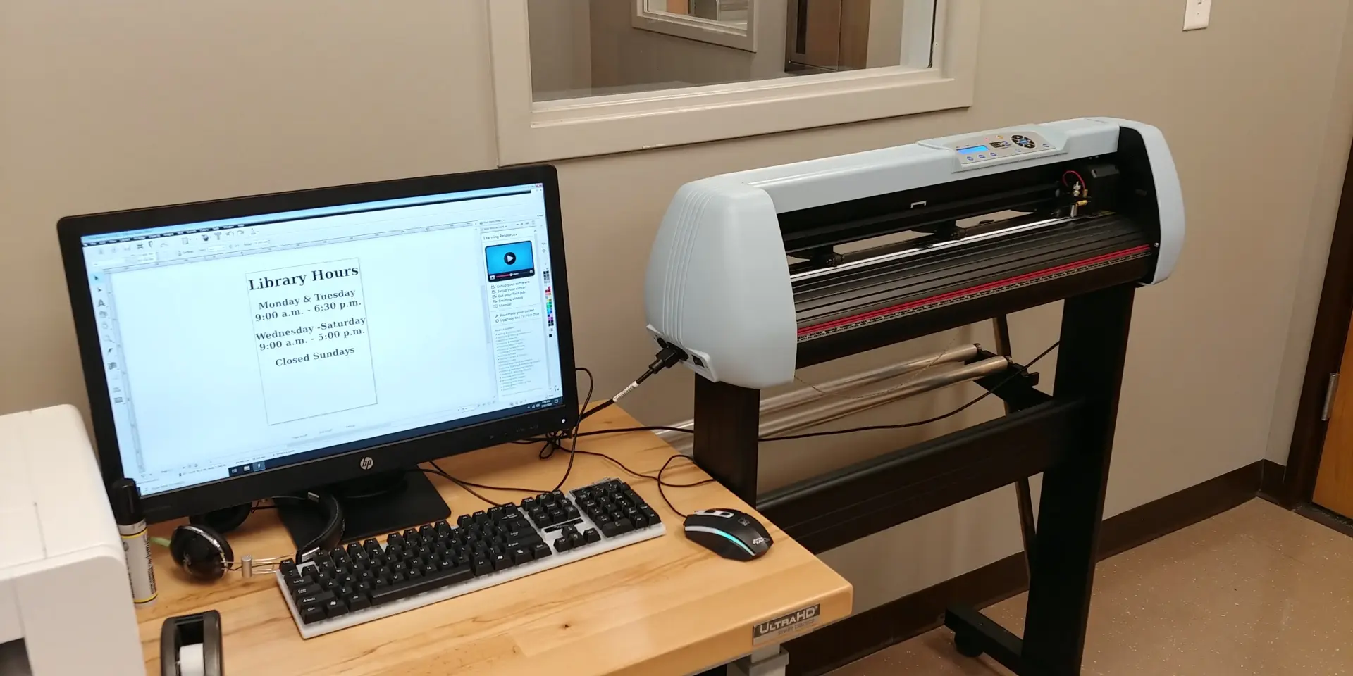 A Vinyl Cutting machine sits aside a computer with plotting software.